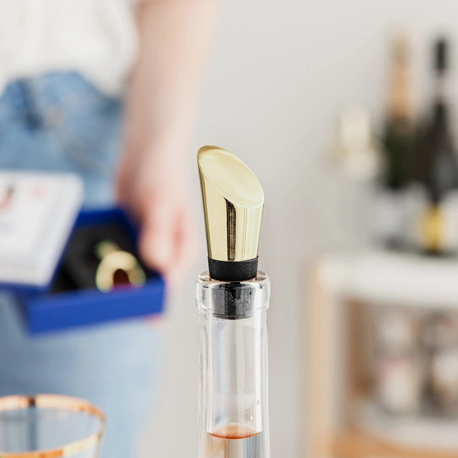 lifestyle photo of wine bottle with heavyweight wine stopper with a gold polished mirror finish with black silicon base 